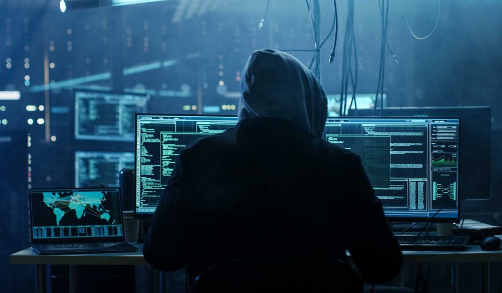 Hooded hacker sitting at a computer