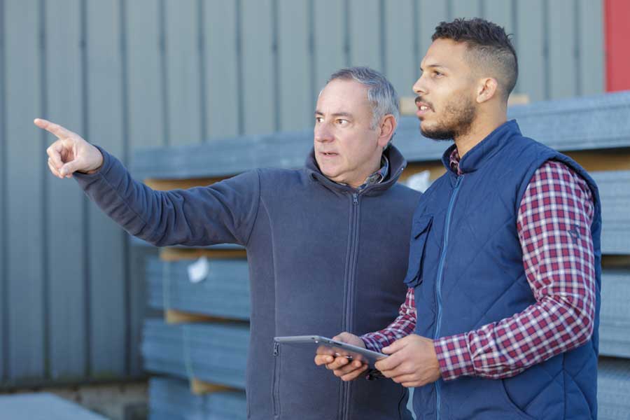 Experienced worker points out something to novice worker while training in the field.